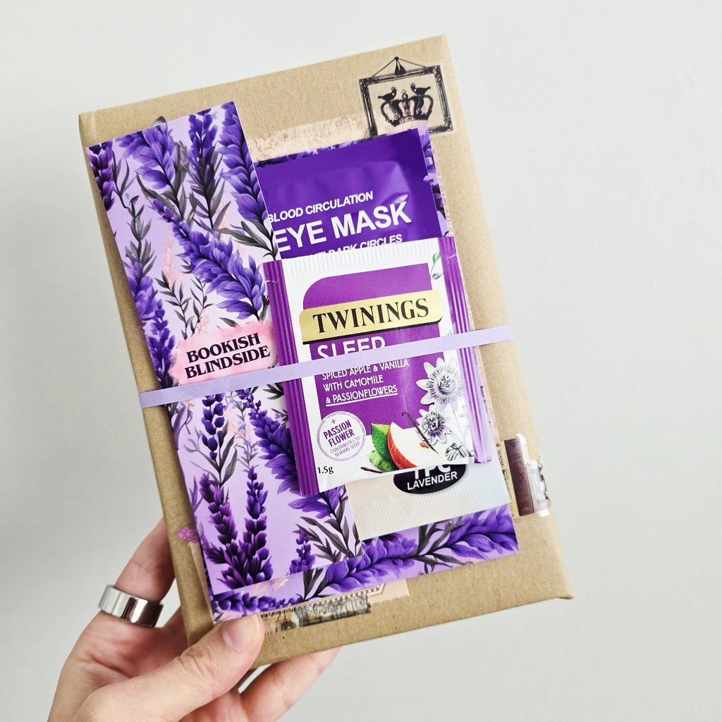 Hand holding a gift box with Twinings tea packaging and an eye mask.